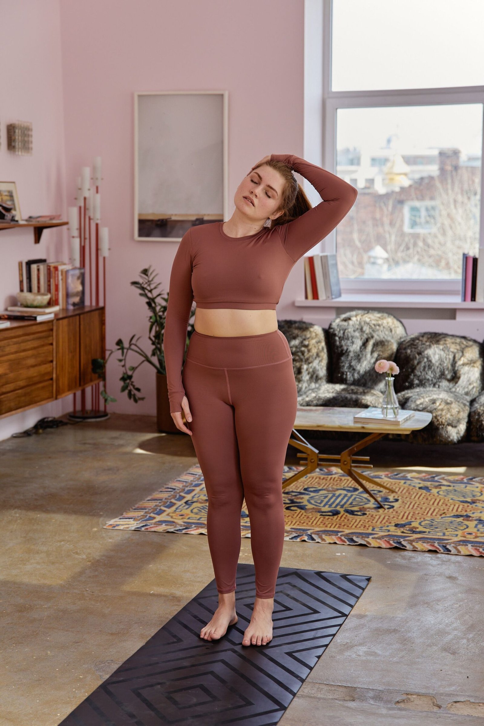 Woman practicing a gentle standing neck stretch at home